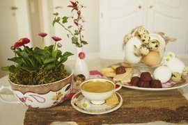 Tischdeko Ostern auf Holzbrett, Kirschblüte, Bellis, Eier, Kaffee, Porzellan, Federn